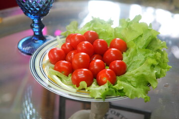 Cherry tomatoes, lettuce and blue glass goblets on the table