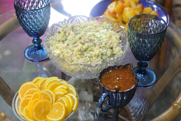 Olive salad, fried potatoes, lemons and glasses on a glass table