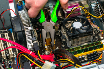 a master with pliers in his hand repairs an old dusty computer