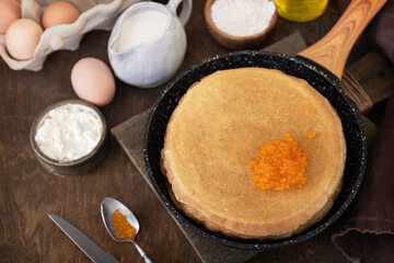 Pancakes traditional Russian cuisine. Thin lacy pancakes served with red caviar on a wooden table.