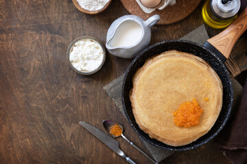Pancakes traditional Russian cuisine. Thin lacy pancakes served with red caviar on a wooden table. Top view flat lay background. Copy space.