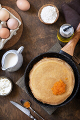 Pancakes traditional Russian cuisine. Thin lacy pancakes served with red caviar on a wooden table. Top view flat lay background.