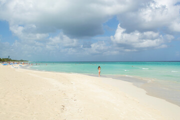 Fototapeta na wymiar Wonderful white sandy beach, tourists and Caribbean sea,many dark clouds background, Varadero ,Cuba