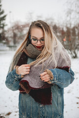 stylish hipster woman standing in snowy city street. beautiful fashionable girl with red lips in warm clothes in cold weather with wind