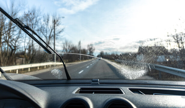 Snow covered car window with wipers, macro, close up. Car wiper blades  clean snow from car windows. Flakes of snow covered the car. Industrial  Stock Photos