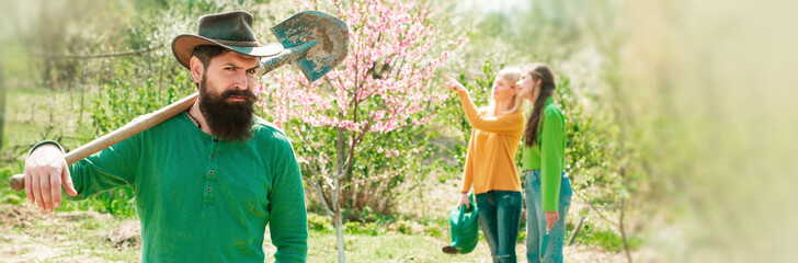 Group of youth work in spring yard with garden tools. A group of friends enjoy the spring nature and take care of the plants. Spring couple in love, banner.
