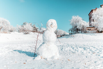 A big snowman on a snowy field. Clear frosty weather. Winter holidays