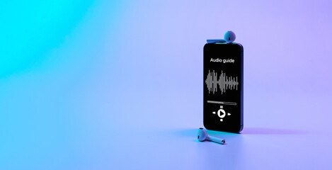 Audio guide online app on digital mobile smartphone screen with music headphones on neon background. Devices for listening audioguide to excursions.