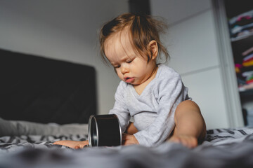 One caucasian baby girl nine months old playing alone on the bed at home in day or morning copy space childhood and growing up concept