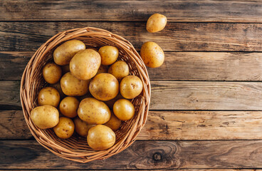 Fresh raw baby potato in a basket over wooden background.