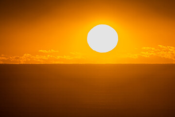 A large sun rises over the ocean at dawn during a heatwave. Australia.