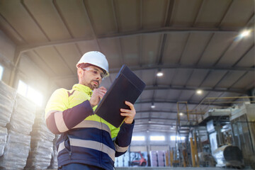 An engineer man making notes on his clipboard in a factory. Concept of Industry