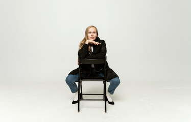 chic fashion model in full growth sitting on a chair on a white background.blonde of European...