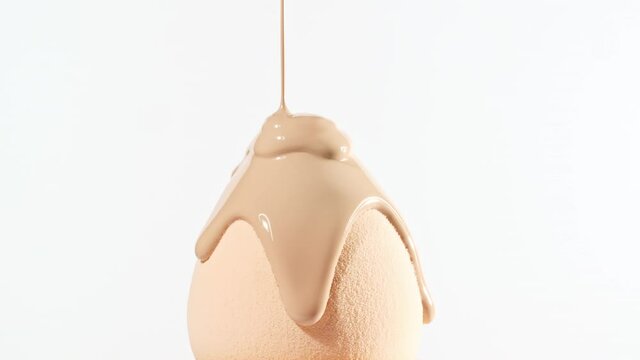 Make-up liquid beige foundation pouring on sponge, closeup. Cosmetic Dripping bb Cream on makeup brush on white background. Macro Shot. Beautiful Makeup concept. High quality 4k footage