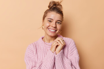 Tender good looking woman with combed hair keeps hands together smiles gently receives hearwarming...