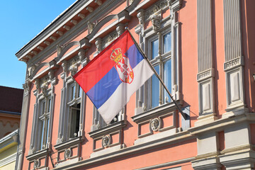 Serbian flag displaying on a pole in front of the building.