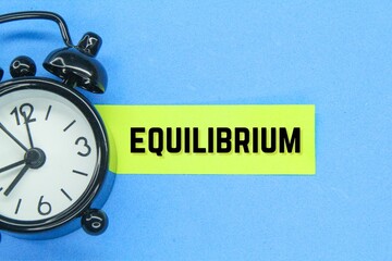an alarm clock and a yellow paper with the word equilibrium