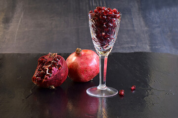 Pomegranate fruits and pomegranate seeds in a glass.