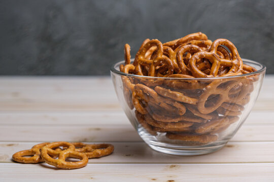 Salted mini pretzels in a deep glass bowl on a wooden tabletop. Popular beer snack. Space for text.