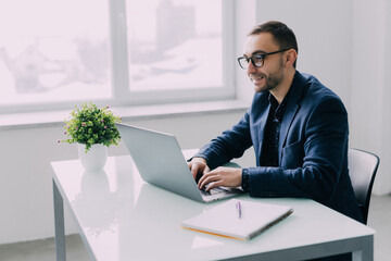 Young handsome business man working at home with laptop and papers on desk