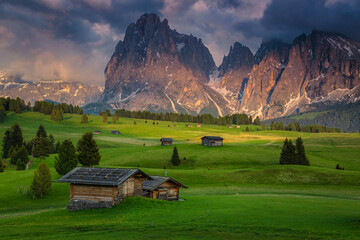 Spring alpine landscape and wooden chalets on the fields, Dolomites