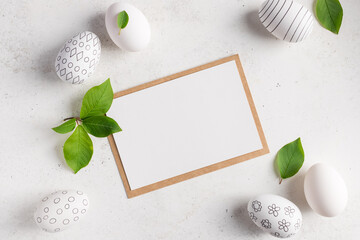 Fototapeta na wymiar flat lay composition with blank paper card and easter eggs with pattern on white background. Happy Easter greeting card. place for text