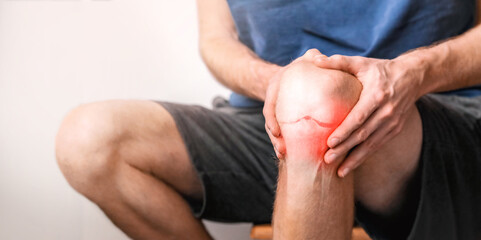 Young man suffering from knee pain at home, close up.  Joint inflammation concept. 