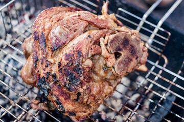 Grilled juicy pork knuckle. Appetizing knuckle or boar hoof. Cooking pork leg on coals. Close-up....