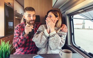 Happy couple excited talking and joking looking at camera on video call from their campervan