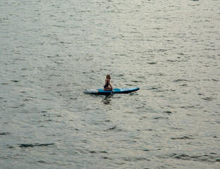 Fototapeta na wymiar a lonely girl on a SUP-board swam far out to sea.