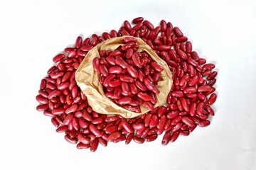 Red bean seeds in brown paper bag on white background, top view.
