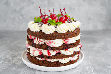 Naked Black forest cake, Schwarzwald pie. Cake with dark chocolate, whipped cream and cherry on a gray concrete background. Copy space.
