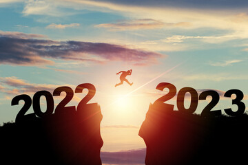 Welcome merry Christmas and happy new year in 2023,Silhouette Man jumping from 2022 cliff to 2023...