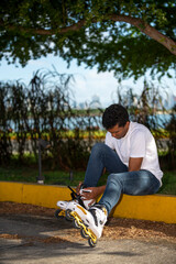 Young latino man sitting putting on inline skates