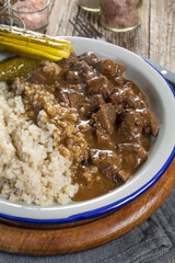 Beef stew served with barley and pickled cucumber.