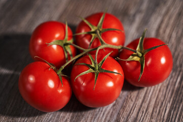 red tomatoes on a branch on a wooden background
