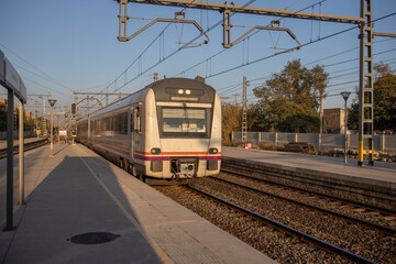 Obraz premium Passenger train in motion at the station in the evening. Rail travel. Modern intercity train on a railway platform. Passenger train on the railway in the evening.