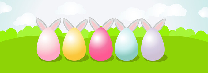 Large painted eggs stand on the green grass and the ears of the Easter Bunny stick out from behind. A long horizontal banner depicting a beautiful spring day and a green field or meadow and a blue sky