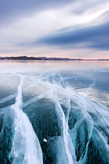 Large cracks in the clear smooth blue ice of Lake Baikal at sunset. Siberia Russia