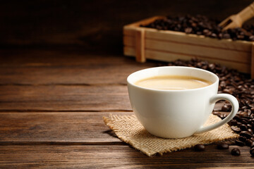 Coffee cup and coffee beans on a wooden background.