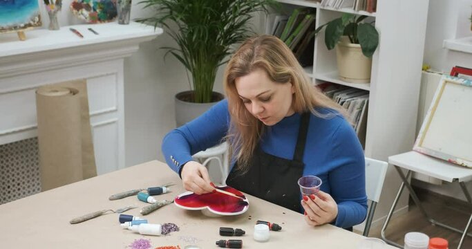 Woman crafting big heart from epoxy resin for Valentine's Day. Handmade gifts and presents for beloved. Handicrafts from epoxide material
