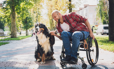 Happy young man with a physical disability who uses wheelchair with his dog.