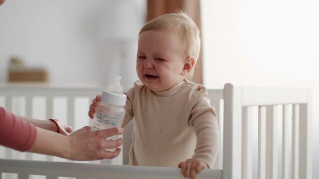 Little Baby Crying While Standing In Bed, Unrecognizable Mother Soothing Upset Child