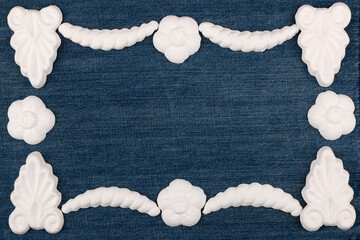 Empty frame made of white plaster stucco laying on denim