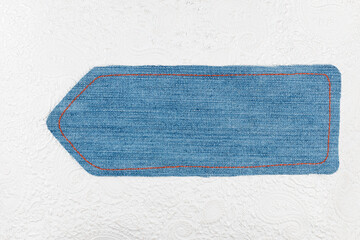Empty denim arrow with space for design, space for text. Pointer lying on white decorated leather - 482155286