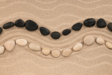Fototapeta na wymiar Curved line of white and black stones lying on the dunes. With space for design, text place