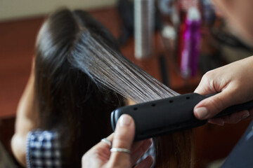 hairdresser's hands make corrugation with a device on long hair