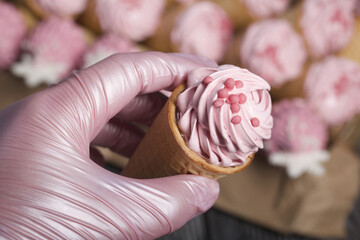 A woman holds marshmallows in waffle cones in her hand. Decorated with decorative sprinkles and mastic snowflakes. Close-up.