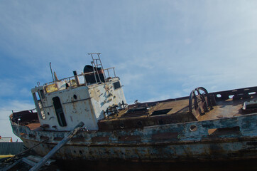 A small abandoned rusty ship stands in the open air. Summer.