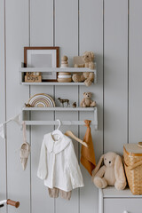 Children's things on a gray wooden wall Toys and clothes for a child Teddy bear and a wooden pyramid